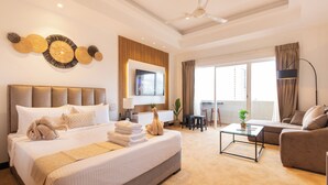A hotel room with a large bed, a sofa, a coffee table, a TV, and a balcony with curtains. - The newest Luxury at the heart of Negombo. (Negombo)