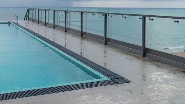 A swimming pool with a glass barrier and a view of the sea under cloudy skies. - The newest Luxury at the heart of Negombo. (Negombo)
