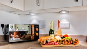 Una cocina moderna con horno integrado, encimera de madera y diversos alimentos, como pan, queso, aceitunas y uvas.