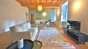 A living room with a sofa, a coffee table, a TV stand, and a kitchen area in the background.
