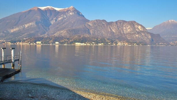 A lake with mountains in the background and a pier extending into the water.