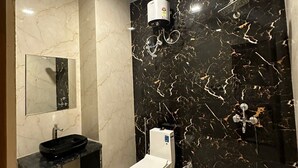 A modern bathroom with a black marble wall, a white toilet, and a black sink. - The Black Eagle Resort (Pushkar)