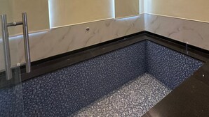 A modern bathroom with a built-in pool, wooden ceiling, and marble walls. - The Black Eagle Resort (Pushkar)
