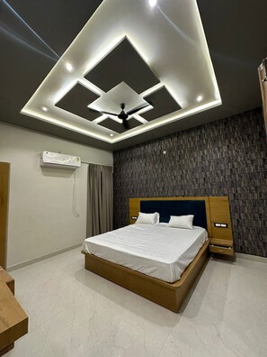 Relax in a stylish room with a central bed, ceiling fan, and geometric light fixture.