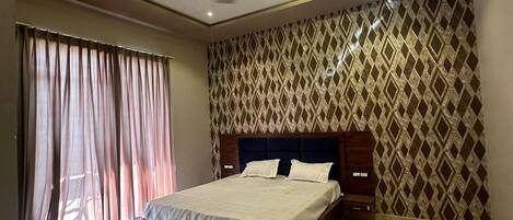 A modern bedroom with a large bed, a ceiling fan, and patterned wallpaper.