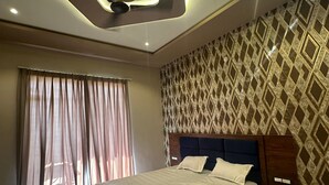 A modern bedroom with a large bed, a ceiling light fixture, and patterned wallpaper. - The Black Eagle Resort (Pushkar)