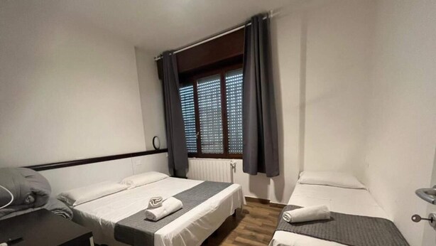 Een hotelkamer met twee enkele bedden, een bureau en een raam met zonwering.