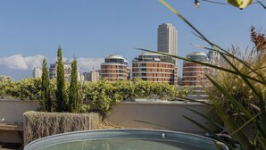 Zona de piscina al terrat amb vista a edificis de la ciutat.