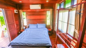 Ein Zimmer in einer Holzhütte mit einem Bett, einem Nachttisch und einem Fenster mit Vorhängen.