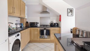 Een moderne keuken met houten kastjes, een ingebouwde oven, een vaatwasser en een koffieapparaat.