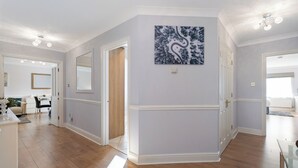 Een ruime kamer met houten vloeren, een grote spiegel en een modern abstract schilderij.