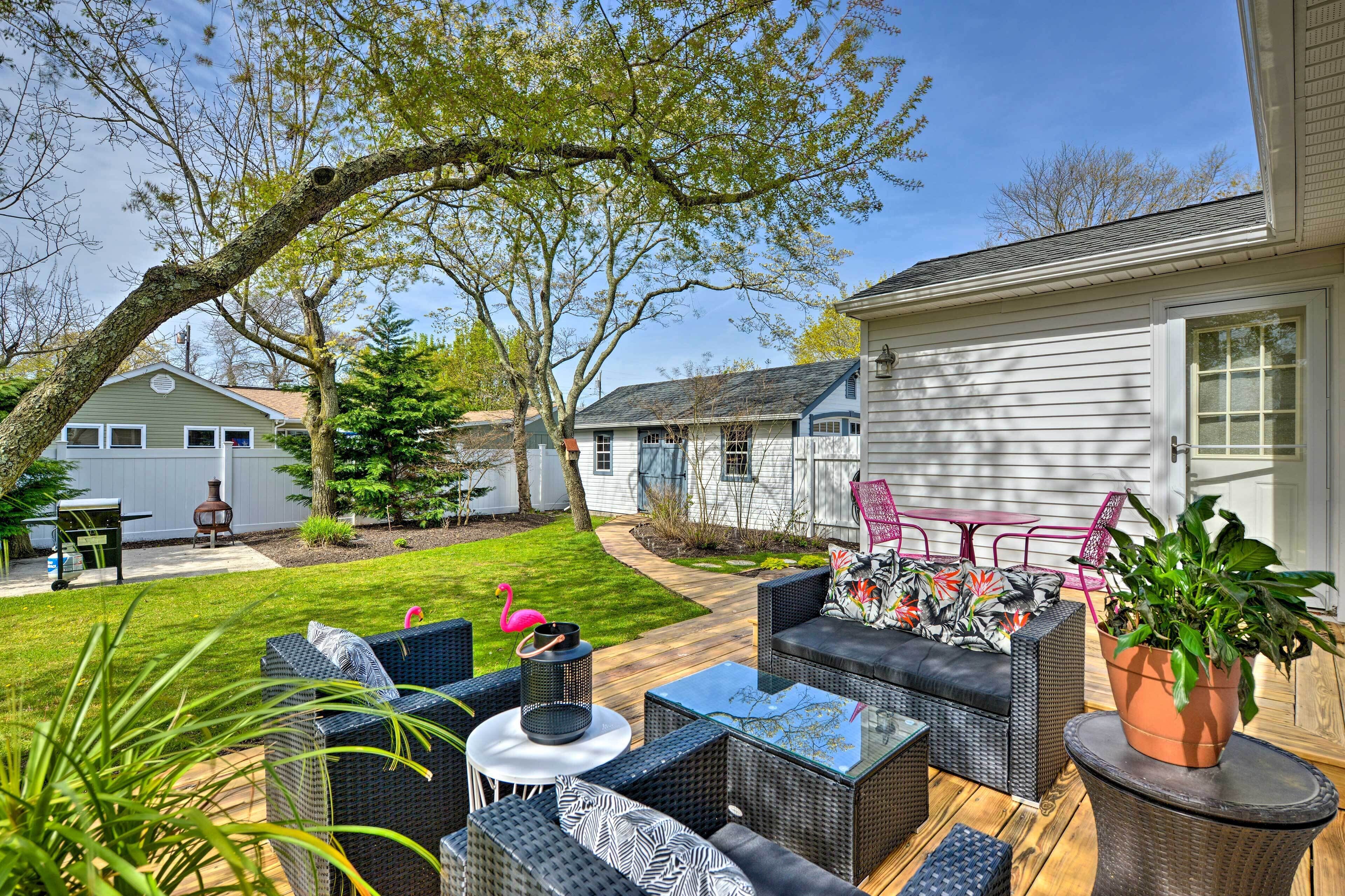 An outdoor patio with wicker furniture, a glass table, and a potted plant.