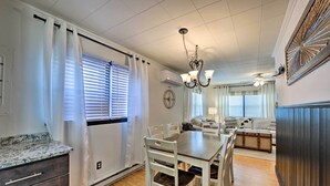 A dining area with a table and chairs, a chandelier, and a kitchen area with cabinets and a countertop.