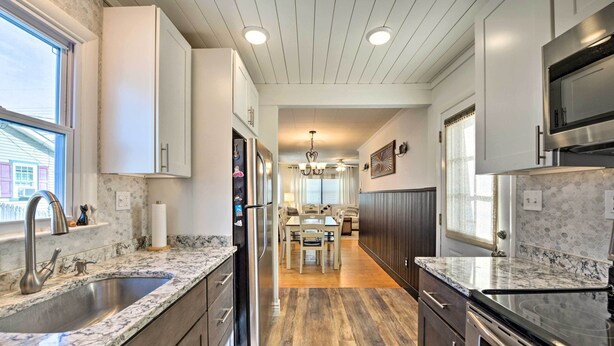 A modern kitchen with granite countertops, stainless steel appliances, and a wooden floor.