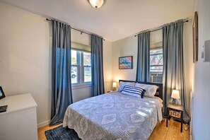 A bedroom with a bed, bedside tables, a desk, and curtains.