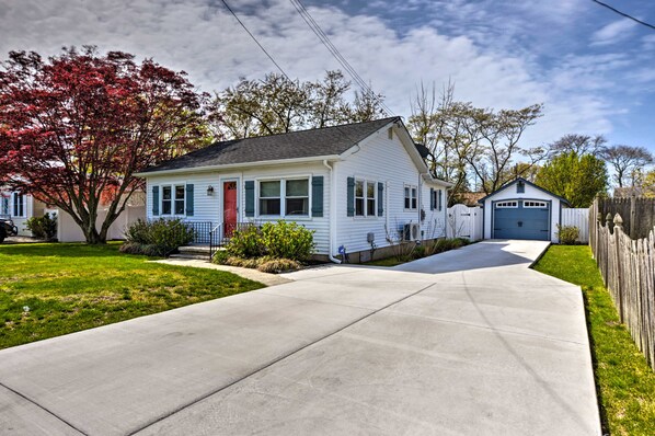 A single-story house with a front porch, a garage, and a small shed.