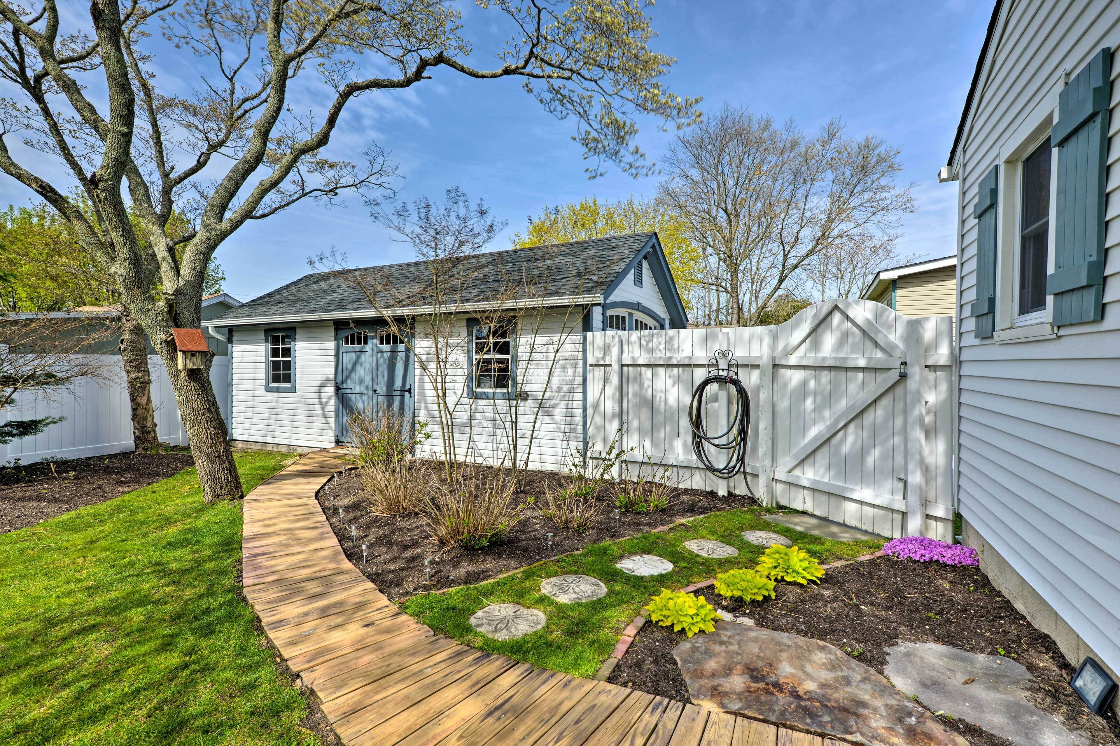 A residential backyard with a wooden deck, a stone pathway, and a fenced area with a garden.