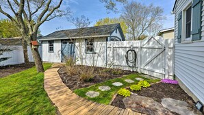 A residential backyard with a wooden deck, a stone pathway, and a fenced area with a garden.