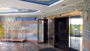 A hotel entrance with a sign reading "TOP RANK HOTELS GALAXY" and a modern design with marble walls and a glass door. - Top Ranks Hotel Galaxy (Yenagoa)