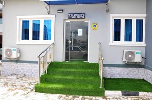A fitness center entrance with a staircase, air conditioning units, and a sign above the door. - Top Ranks Hotel Galaxy (Yenagoa)