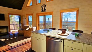 L’intérieur d’un chalet en bois comprend une cuisine, un coin repas et une cheminée.