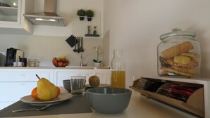 Una cocina con un bol de frutas, un vaso de jugo, una pera, un tazón y un frasco de sándwiches.