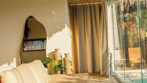 Une chambre dotée d’un grand lit, d’un luminaire suspendu, d’une porte vitrée donnant sur une piscine et offrant une vue sur l’extérieur.