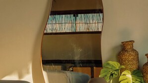 Un salon moderne avec un grand miroir, un canapé, une table basse en bois et une bibliothèque.