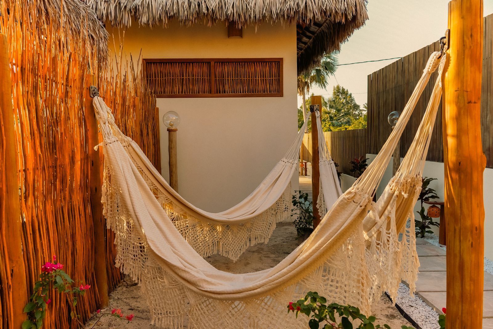 A hammock in a rustic outdoor setting with a thatched roof structure and wooden walls.