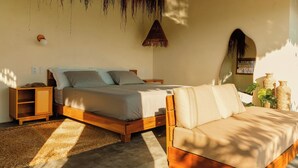 Une chambre à coucher comprenant un lit, une table de chevet en bois, une lampe de chevet, un canapé et un luminaire suspendu.
