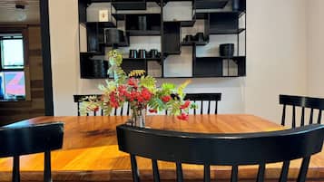 Un comedor con una mesa de madera, sillas negras y un estante negro contra la pared.