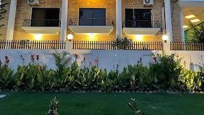 A modern two-story house with a balcony, a well-maintained garden, and a white fence. - Infinity Villa (Islamabad)