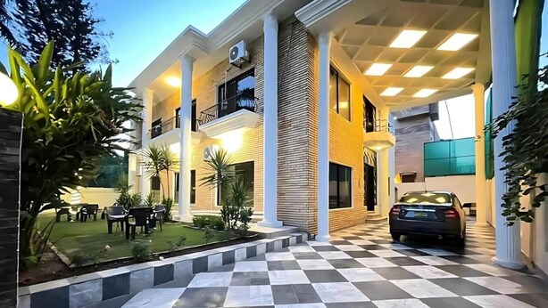 A modern building with a checkered floor, outdoor seating, and a car parked in front. - Infinity Villa (Islamabad)
