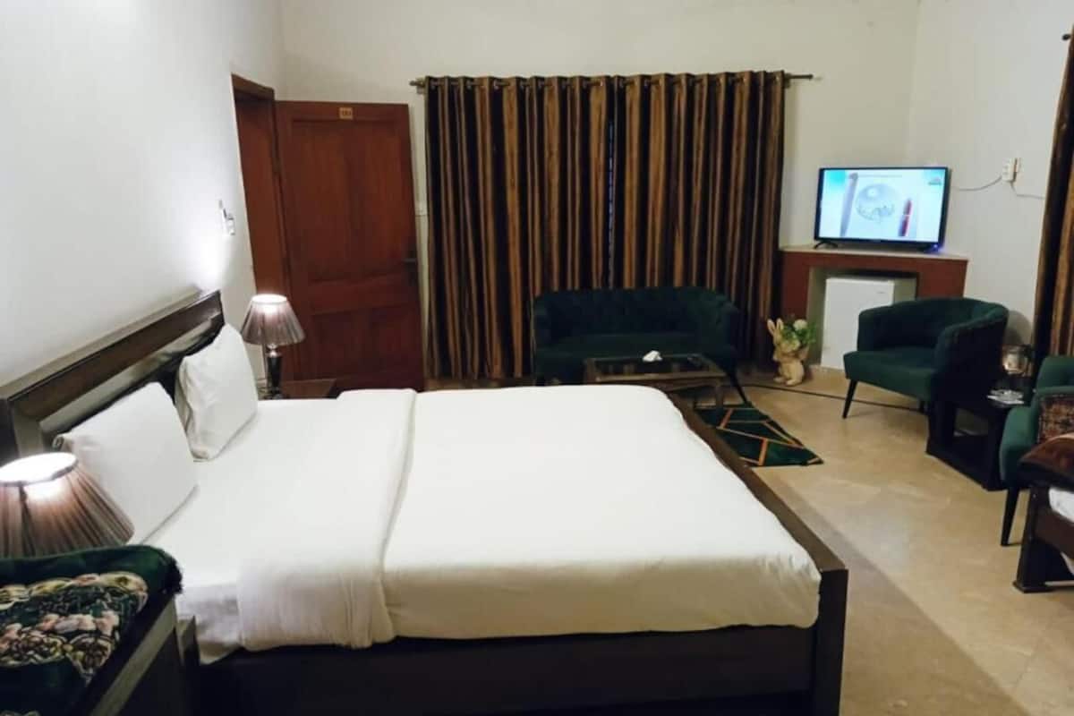 A hotel room with a bed, a television, a desk, a chair, and a curtain.