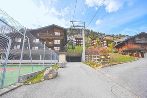 A ski resort with a ski lift, wooden buildings, and a fenced area with a green surface. - 8th floor, balcony, 48m², Les Gets (Les Gets)