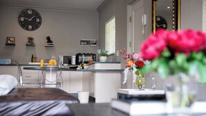 A modern kitchen with a microwave, toaster, and coffee maker. There is a clock on the wall and a potted plant on the counter. - Crown Loft - Bright, Airy Stay with Balcony View (Sandton)
