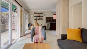 Un salon spacieux comprenant un canapé, une table basse et un fauteuil. Une porte-fenêtre coulissante donne accès à un espace extérieur.
