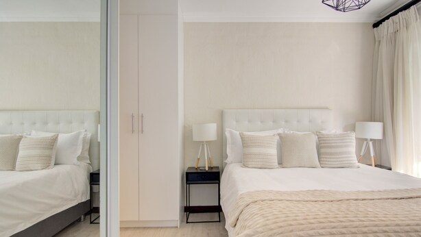 Une chambre à coucher moderne avec un grand lit, des tables de chevet et un miroir.