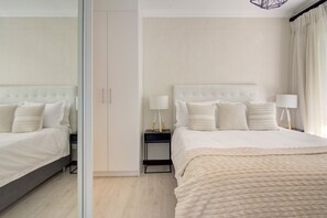 A modern bedroom with a large bed, bedside tables, and a mirror. - Regency Rose - Stylish, Private, Patio & Garden (Sandton)