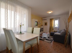A modern living room with a dining area, a sofa, and a TV. - Brigth and Breezy Rovinj Apartments (Rovinj)
