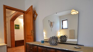 Une chambre à coucher avec une commode en bois, un grand miroir et un lit.