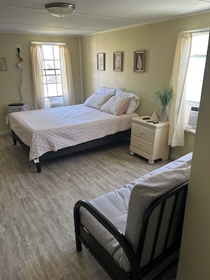 A bedroom with a bed, bedside table, and a window. - Workers Heaven (Daleville)