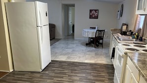 A kitchen with a refrigerator, stove, and dining area. - Workers Heaven (Daleville)
