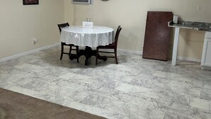 A room with a round table, chairs, a clock, an air conditioning unit, and a door. - Workers Heaven (Daleville)