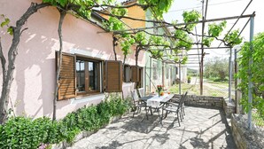 A patio with a table and chairs, a pergola with vines, and a stone wall. - Green and Lush Apartments With Terrace (Rovinj)