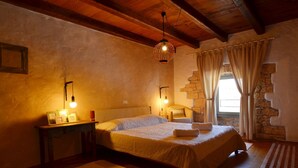 A cozy bedroom with a large bed, two bedside lamps, a wooden headboard, a stone wall, and a window with curtains. - Majestic Rustical Kanfanar Villa With Pool (Kanfanar)