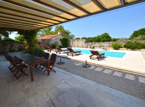 An outdoor patio with a pool, stone walls, and a covered seating area. - Majestic Rustical Kanfanar Villa With Pool (Kanfanar)