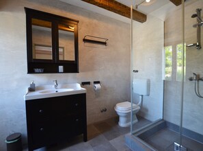 A modern bathroom with a glass-enclosed shower, a white sink, a dark vanity, and a large mirror. - Majestic Rustical Kanfanar Villa With Pool (Kanfanar)