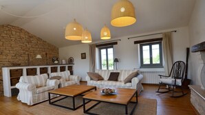 A spacious living room with a stone wall, a sofa set, a coffee table, and hanging wicker lamps. - Majestic Rustical Kanfanar Villa With Pool (Kanfanar)
