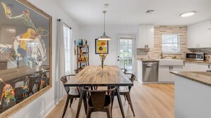 Une cuisine moderne dotée d’un îlot central en bois, de meubles blancs et d’un four à micro-ondes encastré.